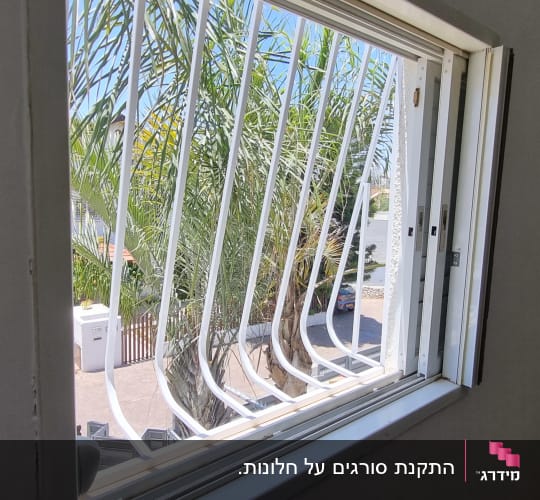 סורגי מתכת לבנים עם בטן המותקנים על חלון בבית